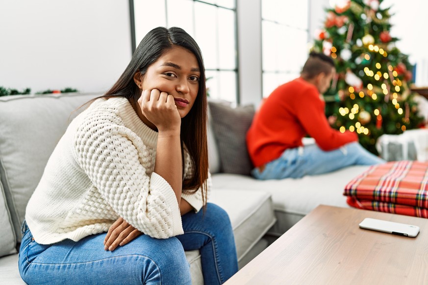 Young latin couple on problems with sad expression sitting on the sofa at home.