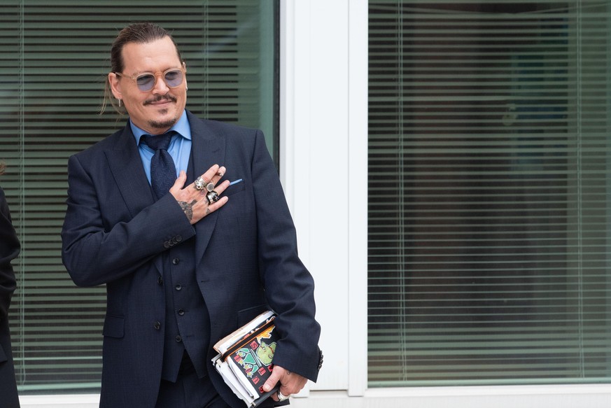 Johnny Depp gestures to fans during a recess in his civil trial with Amber Heard, at the Fairfax County Courthouse, in Fairfax, Friday, May 27, 2022. Depp brought a defamation lawsuit against his form ...