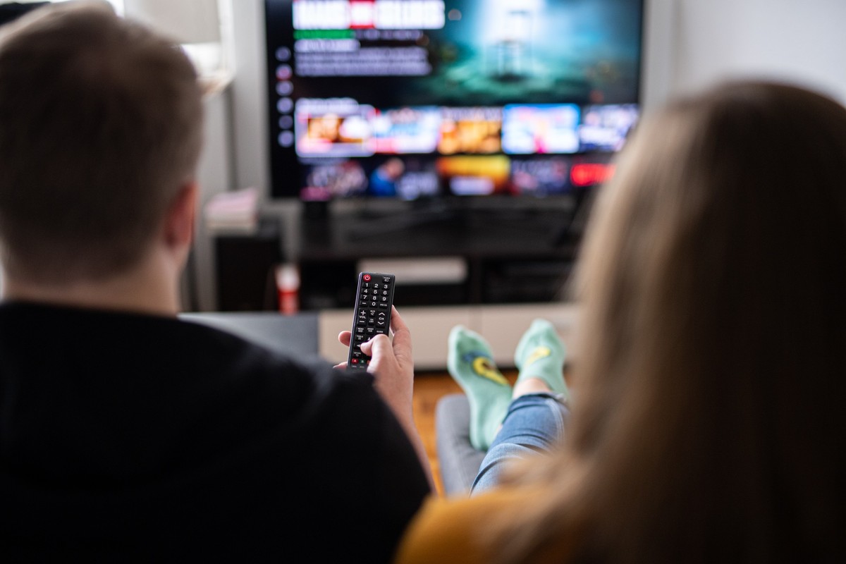 ARCHIV - 14.09.2021, Hamburg: Ein Paar sitzt vor dem Fernseher, der Mann h�lt die Fernbedienung. (zu dpa: �Deutscher Streaming- und Pay-TV-Markt w�chst�) Foto: Daniel Reinhardt/dpa +++ dpa-Bildfunk ++ ...