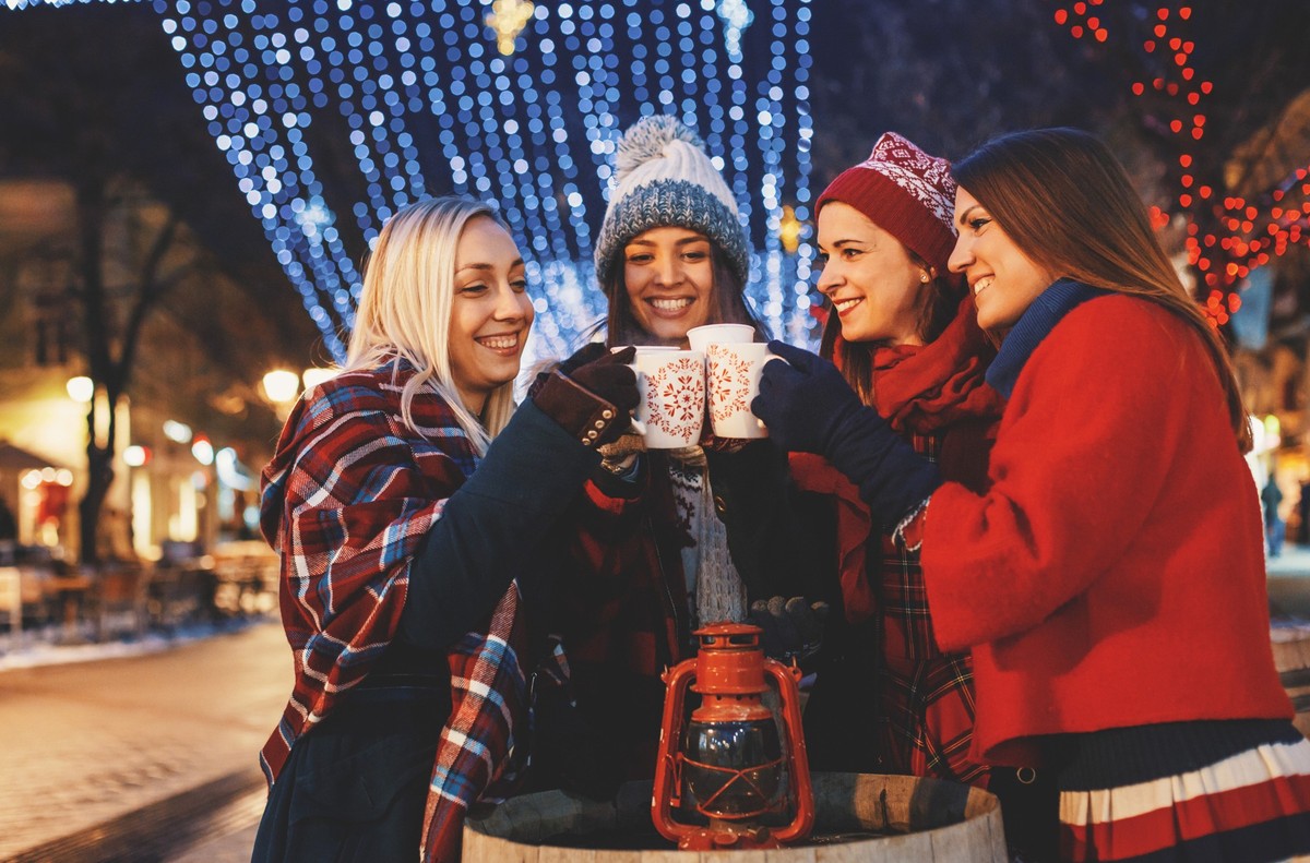 Four friends enjoying mulled wine during Christmas festivities.