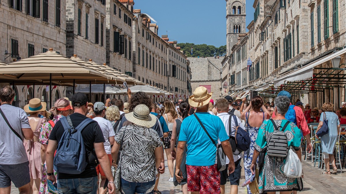 PRODUKTION - 18.07.2023, Kroatien, Dubrovnik: Touristen gehen an dem heißen Tag durch eine Geschäftsstraße von Dubrovnik. Dubrovnik ist bei Touristen schon länger sehr beliebt. Doch mittlerweile ist d ...