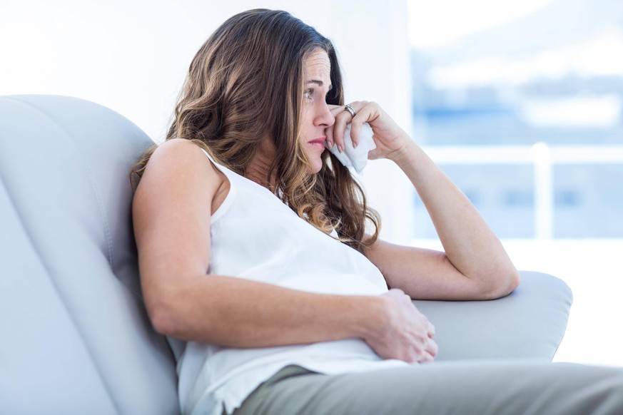 Sad pregnant woman sitting on sofa model released Symbolfoto PUBLICATIONxINxGERxSUIxAUTxONLY Copyright: xWavebreakmediaMicrox Panthermedia15699192