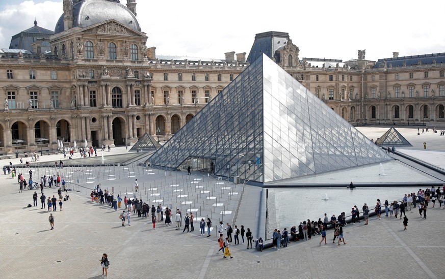 Visitors queue to enter the Louvre Pyramid designed by Chinese-born U.S. architect Ieoh Ming Pei in Paris as the museum reopens its doors to the public after almost 4-month closure due to the coronavi ...