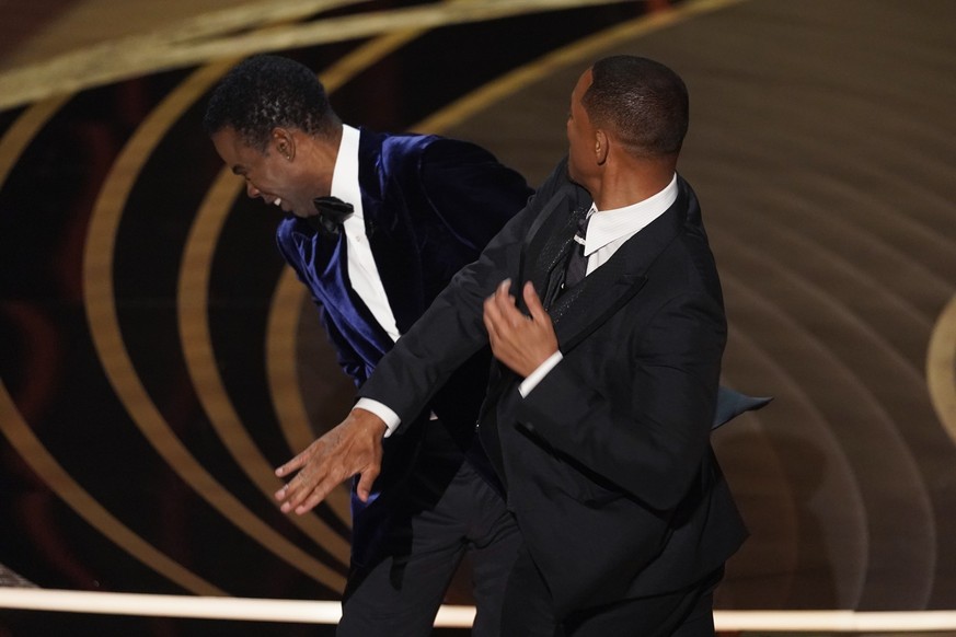 ARCHIV - 28.03.2022, USA, Los Angeles: Will Smith (r), Schauspieler und Sänger aus den USA, schlägt Moderator Chris Rock, Schauspieler aus den USA, auf der Bühne, während er den Preis für den besten D ...