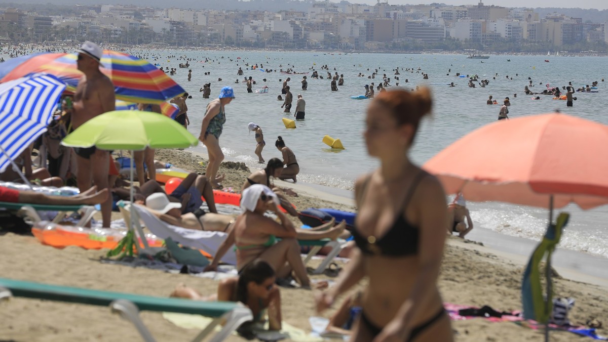 ARCHIV - 18.07.2023, Spanien, Palma de Mallorca: Menschen schwimmen und sonnen sich am Strand von Arenal der Mittelmeer-Insel Mallorca. (zu dpa «Frühe Osterferien bereiten den Mallorca-Hoteliers Sorge ...