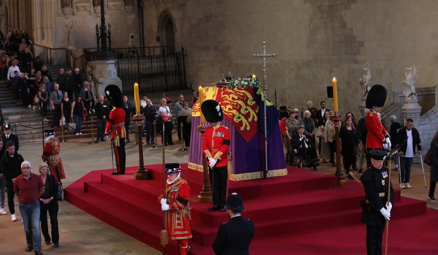 People file past the coffin of Her Majesty Queen Elizabeth II who.will lie in state in Westminster Hall for four days. The coffin is draped with the Royal Standard on which lie the Instruments of Stat ...