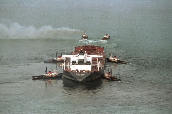 FILE - Tug boats, with smoke pouring from their stacks, pull the tanker Exxon Valdez from a reef in Prince William Sound, Alaska, on April 5, 1989. Jack Smith, an AP photographer who captured unforget ...