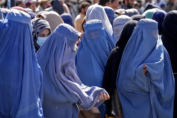 ARCHIV - 15.08.2022, Afghanistan, Kabul: Frauen in Burkas warten auf Lebensmittelrationen, die von einer humanit�ren Hilfsorganisation aus Saudi-Arabien verteilt werden. (zu dpa: &quot;Arbeitsverbot f ...