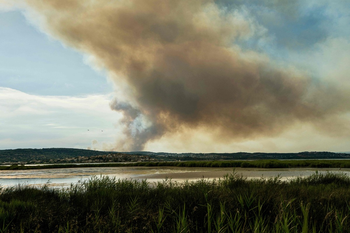 29.06.2025, Frankreich, Bizanet: Dieses Foto zeigt zwei L�schflugzeuge, die westlich der Stadt Narbonne im S�dwesten Frankreichs, in der N�he einer Rauchfahne, verursacht durch einen Waldbrand, an ein ...