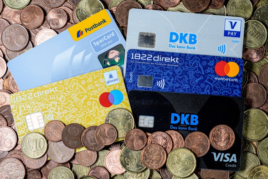 Diverse Kreditkarten, EC-Karten und Sparkassenkarten liegen auf einem Haufen Kleingeld, Kundenkarten der Banken 1822 direkt, Frankfurter Sparkasse, Postbank, VISA, Mastercard und DKB, Kreditkarte, EC- ...