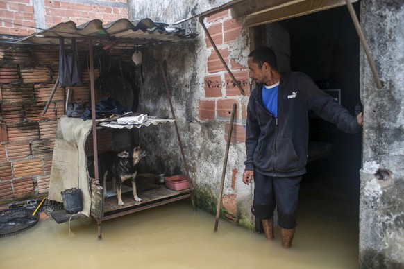 24.03.2024, Brasilien, Duque de Caxias: Ein Mann steht in seinem überfluteten Haus nach schweren Regenfällen. Bei schweren Unwettern sind im Südosten mehrere Menschen ums Leben gekommen. Foto: Bruna P ...
