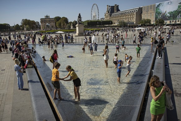 11.08.2022, Frankreich, Paris: Menschen stehen im Brunnen vor dem Louvre-Museum. Frankreich befindet sich bereits in der dritten Hitzewelle diesen Sommer. Praktisch �berall in Frankreich liegen die Te ...