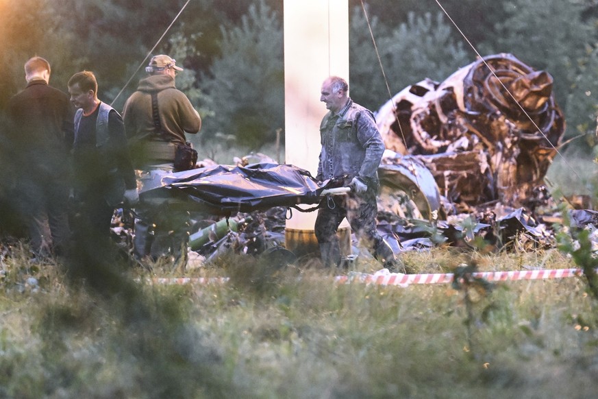 dpatopbilder - 24.08.2023, Russland, Kushenkino: Menschen tragen einen Leichensack aus dem Wrack eines abgestürzten Privatjets in der Nähe des Dorfes Kuschenkino in der Region Twer. Der russische Söld ...