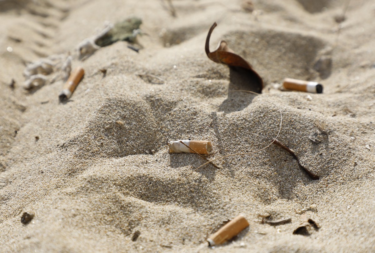 ARCHIV - 15.01.2022, Spanien, Palma: Zigarettenstummel liegen im Sand am Strand von Arenal. Das Rauchen schadet laut Weltgesundheitsorganisation (WHO) nicht nur der Gesundheit, sondern auch der Umwelt ...