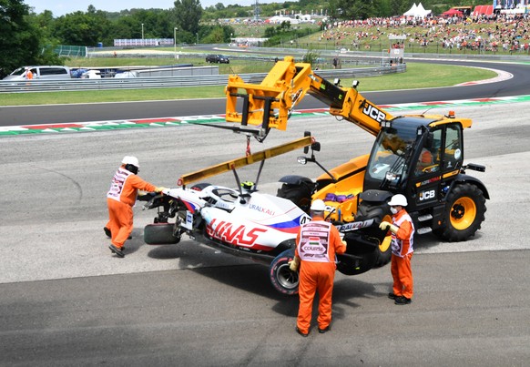 Formula 1 2021: Hungarian GP HUNGARORING, HUNGARY - JULY 31: Marshals remove the damaged car of Mick Schumacher, Haas VF-21, from a tyre barrier after his crash in FP3 during the Hungarian GP at Hunga ...