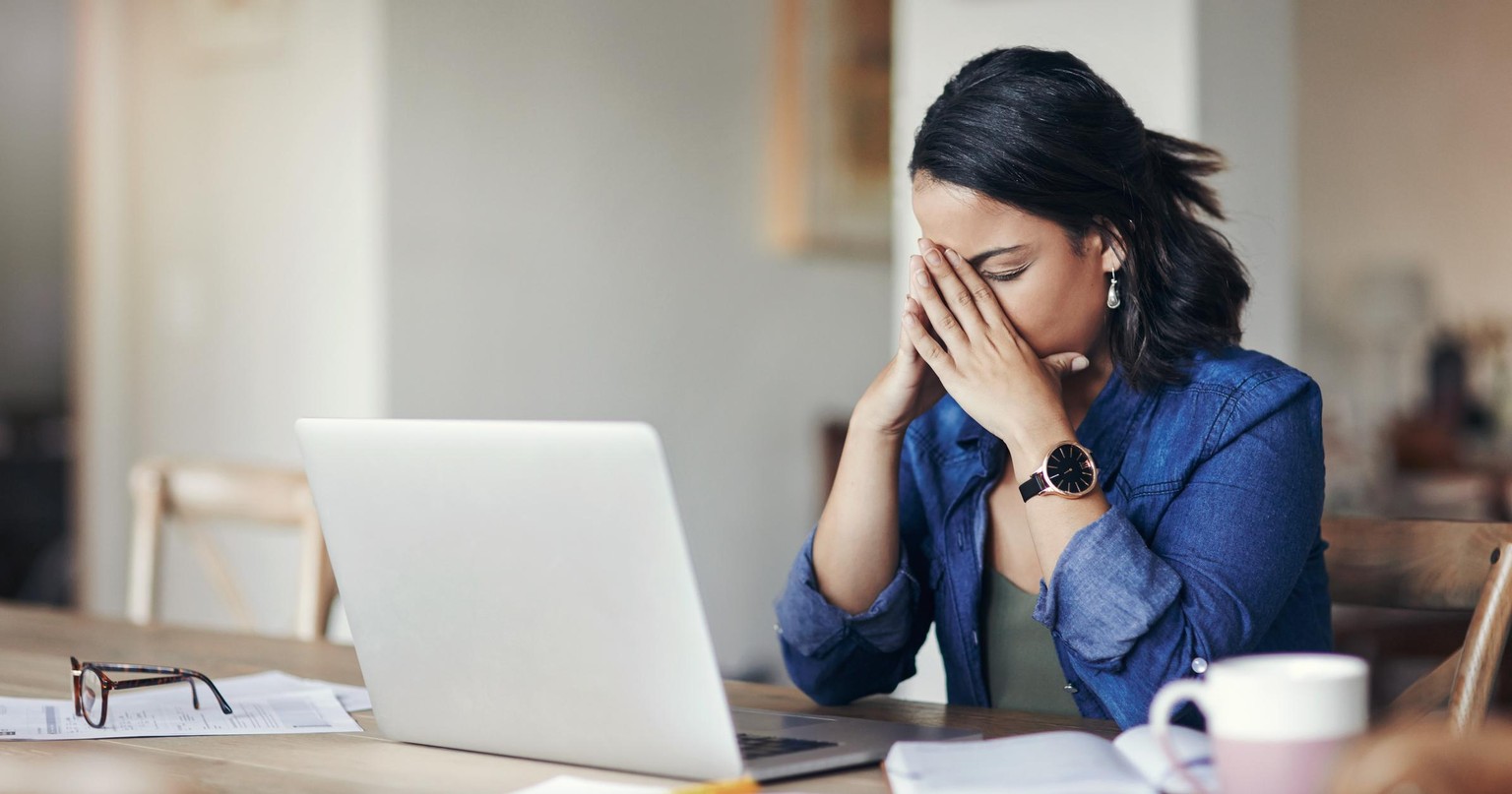 Shot of a young woman looking stressed while using a laptop to work from home