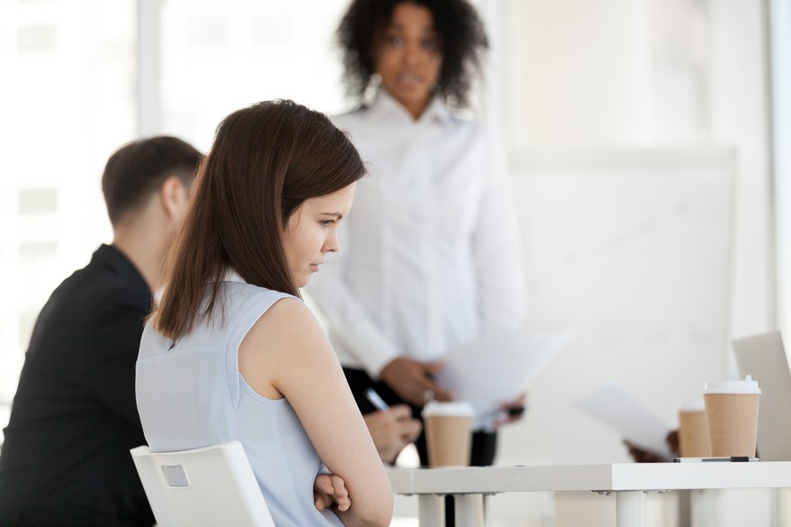 Diverse businesspeople in office during briefing focus on female worker feels guilty unhappy offended and frustrated having problem or disrespect from colleagues or made mistake, listens boss scolding