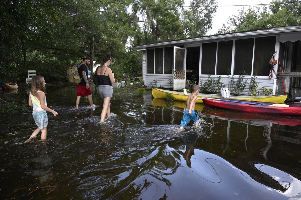 Dustin Holmes, rear, his girlfriend Hailey Morgan, and her children Aria Skye Hall, 7, left, and Kyle Ross, 4, right, arrive to their flooded home in the aftermath of Hurricane Helene, Friday, Sept. 2 ...