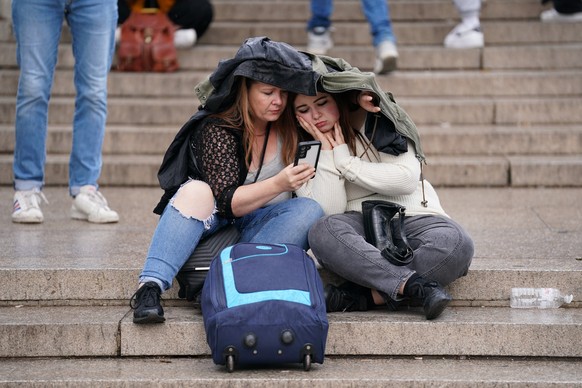 08.09.2022, Gro�britannien, London: Zwei Frauen sitzen am Queen-Victoria-Denkmal vor dem Buckingham-Palast. Die �rzte der britischen K�nigin Elizabeth II. machen sich Sorgen um die Gesundheit der 96 J ...