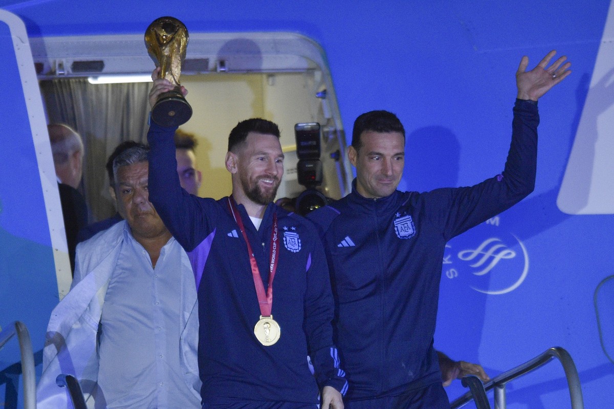 20.12.2022, Argentinien, Buenos Aires: Lionel Messi (l) h�lt den Weltmeisterpokal in der Hand, w�hrend er mit seinem Trainer Lionel Scaloni in Buenos Aires ankommt. Foto: Gustavo Garello/AP/dpa +++ dp ...