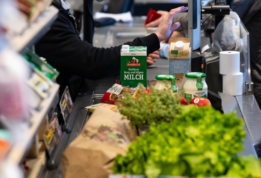 18.01.2023, Bayern, Neubiberg: Lebensmittel liegen in einem Supermarkt an der Kasse auf dem Band. Unter dem Eindruck der hohen Inflation rechnen die Verbraucherverb