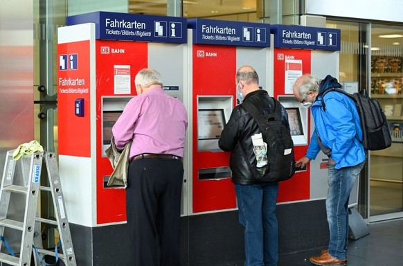 Travellers stand at a ticket vending machine of the Deutsche Bahn at the main railway station in Dortmund on June 1, 2022. - The &quot;9-Euro-ticket&quot;, a flat rate monthly subscription that allows ...