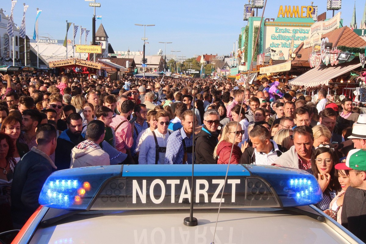 Notarzt Einsatzfahrzeug mit Blaulicht steht nach einer Schlägerei mit verletzten Opfern an einem Festzelt in der Menschenmenge auf dem Oktoberfest in München, Bayern, Deutschland Emergency doctor emer ...