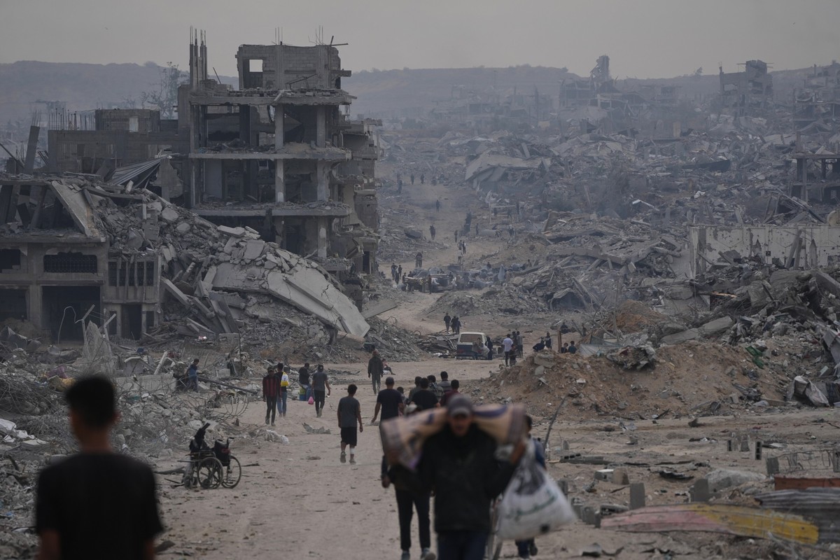 12.10.2025, Palästinensische Gebiete, Gaza: Vertriebene Palästinenser gehen mit ihren Habseligkeiten die stark beschädigte Al-Jalaa-Straße in Gaza-Stadt entlang, nachdem Israel und die Hamas eine Paus ...