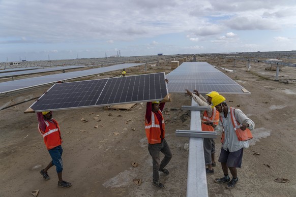 Workers install solar panels at the under-construction Adani Green Energy Limited&#039;s Renewable Energy Park in the salt desert of Karim Shahi village, near Khavda, Bhuj district near the India-Paki ...