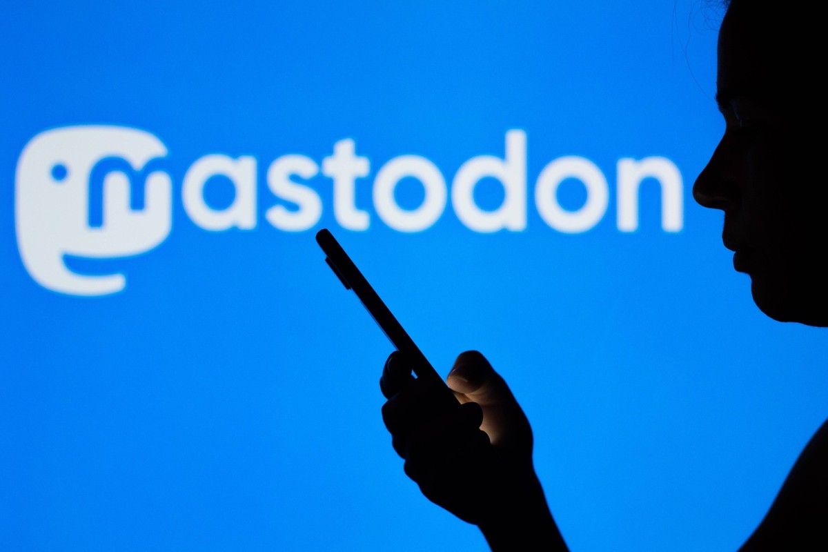 April 21, 2022, Brazil. In this photo illustration the Mastodon logo seen in the background of a silhouette woman holding a mobile phone. April 21, 2022, Brazil. In this photo illustration the Mastodo ...