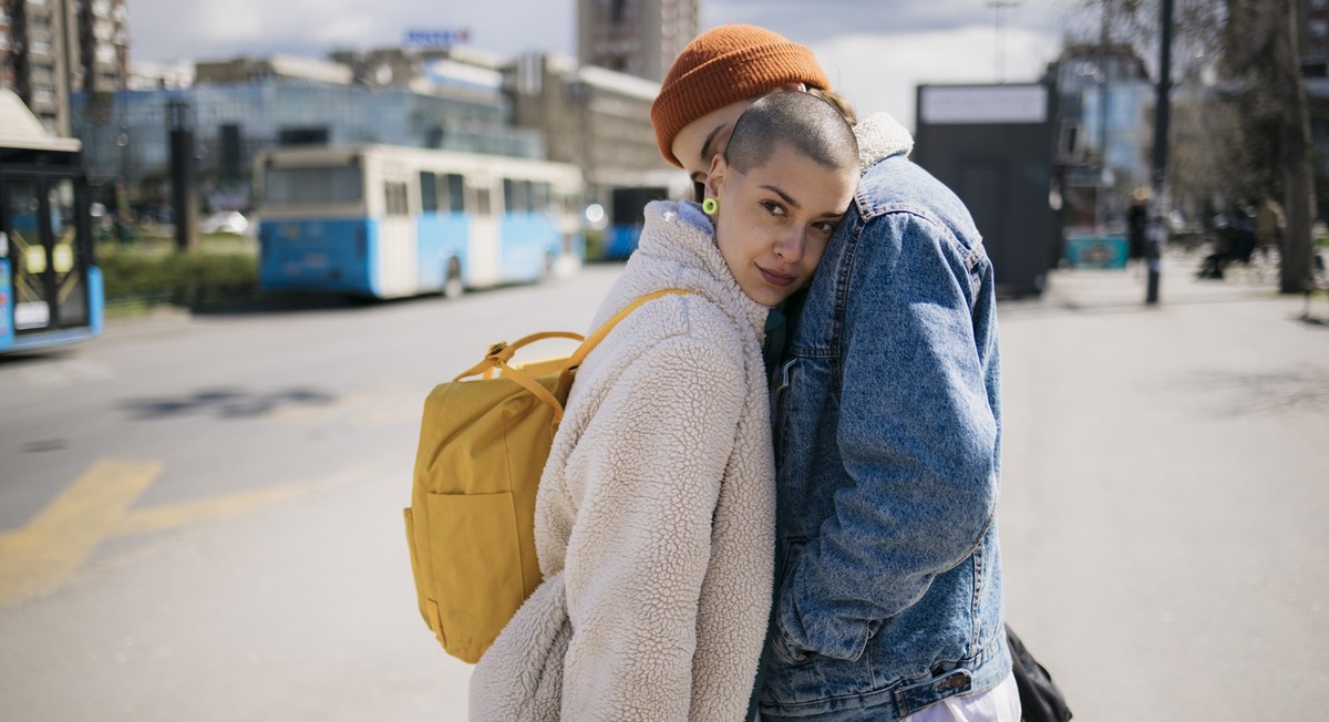 Female friends greeting each other good bye with a hug outside in the city. Two women couple greet at the train station before leaving for vacations.