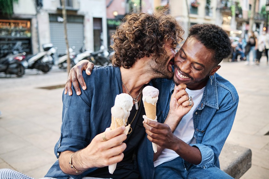 Smiling gay couple romancing while holding ice cream cones model released Symbolfoto AGOF00134