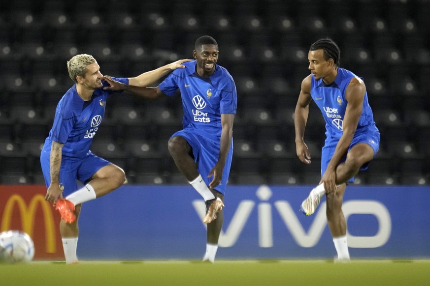 Ousmane Dembele, center, streches with Jules Kounde, right, and ANtoine Griezmann during a training session at the Jassim Bin Hamad stadium in Doha, Qatar, Monday, Nov. 28, 2022. France will play in t ...