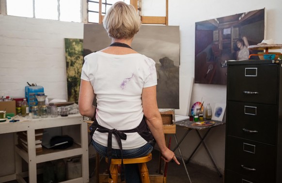 Rear view of woman painting on canvas in drawing class || Modellfreigabe vorhanden