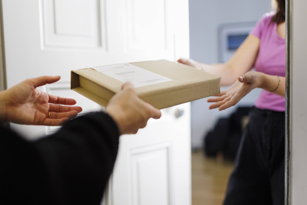 Eine Frau nimmt an einer Wohnungstuer ein Paket entgegen. Berlin, 08.08.2024. Berlin Deutschland *** A woman accepts a parcel at the door of an apartment Berlin, 08 08 2024 Berlin Germany Copyright: x ...
