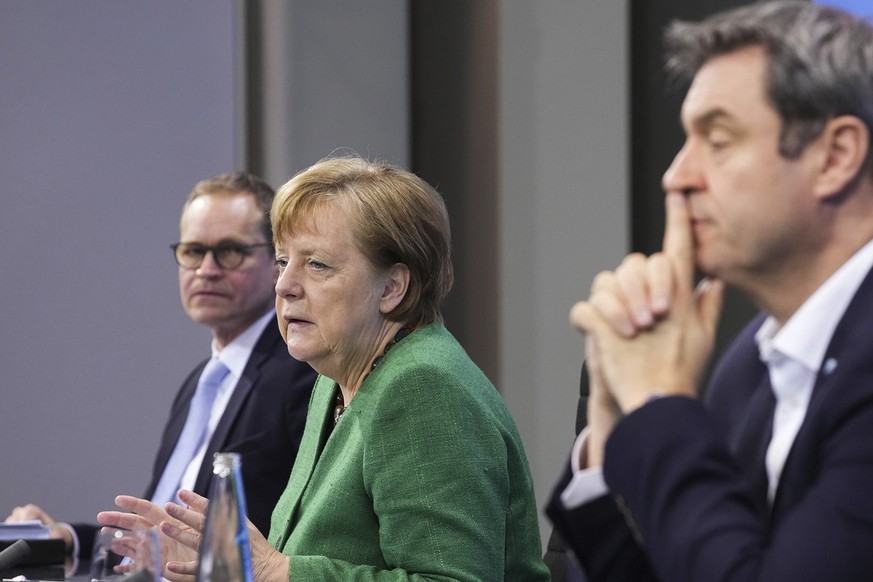 German Chancellor Angela Merkel speaks as Berlin&#039;s Governing Mayor Michael Muller, left, and Bavaria&#039;s Prime Minister Markus Soder, right, listen during a press conference in the Chancellor& ...