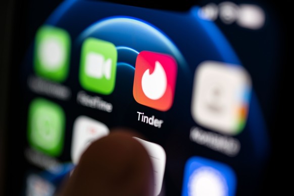 PRODUKTION - 02.09.2022, Baden-Württemberg, Stuttgart: ILLUSTRATION - Eine Hand tippt auf die Tinder-App, die auf einem Smartphone installiert ist. Die Dating-App startete am 12. September vor zehn Ja ...