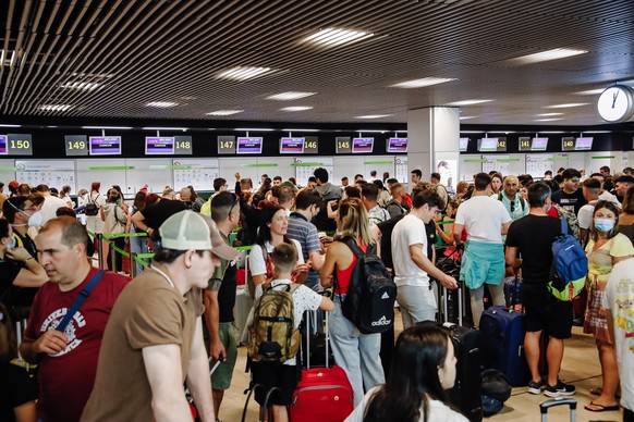 ARCHIV - 01.07.2022, Spanien, Madrid: Passagiere warten im Terminal 1 des Flughafens Adolfo Suarez Madrid Barajas an den Check-in-Schaltern einer Fluggesellschaft. Auch an den Flugh�fen des beliebten  ...