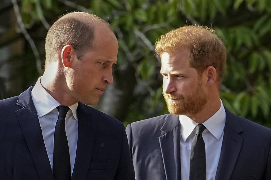 ARCHIV - 10.09.2022, Großbritannien, Windsor: William (l), Prinz von Wales, und Prinz Harry, Herzog von Sussex, gehen nebeneinander, nachdem sie die Blumendekoration für die verstorbene Königin Elizab ...