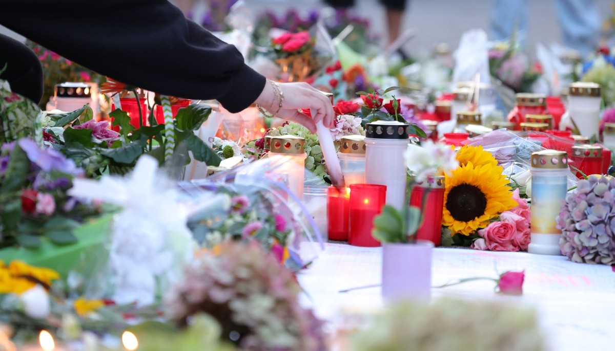 25.08.2024, Nordrhein-Westfalen, Solingen: Nach der Messerattacke auf dem Solinger Stadtfest legen Menschen in der Nähe des Tatortes Blumen nieder und und zünden Kerzen zum Gedenken der Opfer an. Bei  ...