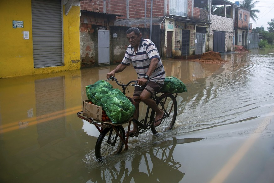 24.03.2024, Brasilien, Duque de Caxias: Ein Anwohner fährt nach heftigen Regenfällen auf einer überfluteten Straße. Bei schweren Unwettern sind im Südosten mehrere Menschen ums Leben gekommen. Foto: B ...