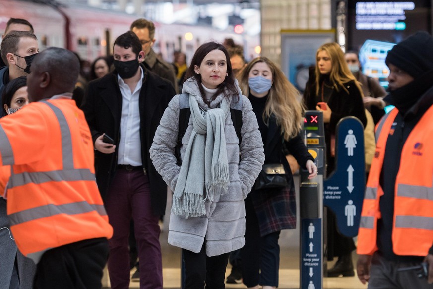 LONDON, UNITED KINGDOM - FEBRUARY 22, 2022: Commuters, some continuing to wear face masks, arrive at Waterloo station during morning rush hour as all of England's remaining Covid restrictions are set  ...