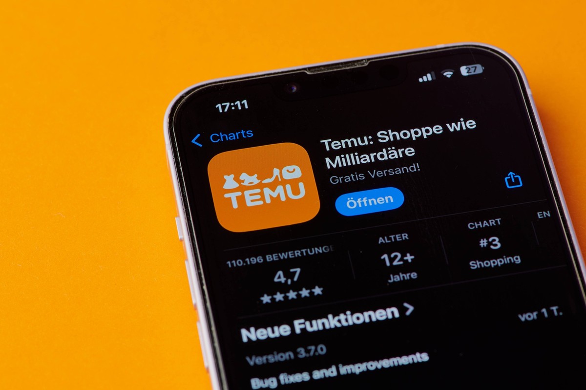 Mainz, Deutschland - 24. Oktober 2024: Icon der Temu-Shopping-App auf einem Smartphone-Bildschirm auf orangem Hintergrund 1103503090