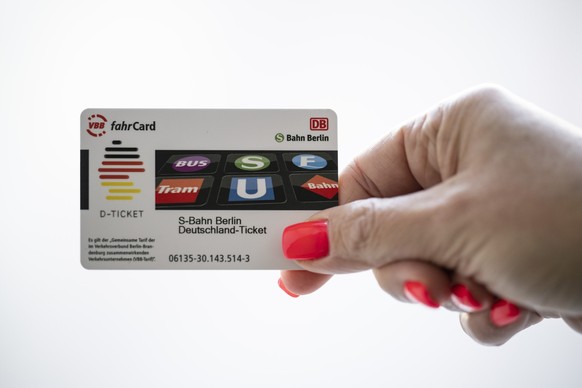 ARCHIV - 03.04.2023, Berlin: Die Hand einer Frau hält eine Deutschland-Ticket-Chipkarte in der Hand. Zwei Wochen vor dem Start des Deutschlandtickets haben Verbraucherschützer vor einer Einschränkung  ...