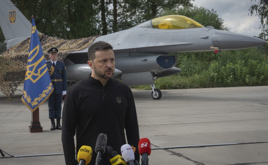 04.08.2024, Ukraine, ---: Der ukrainische Präsident Wolodymyr Selenskyj beantwortet Fragen der Journalisten vor Kampfjets vom Typ F-16 der ukrainischen Luftwaffe. Foto: Efrem Lukatsky/AP/dpa +++ dpa-B ...