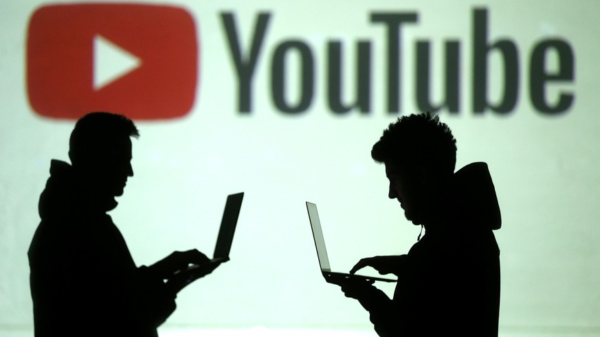 FILE PHOTO: Silhouettes of users are seen next to a screen projection of the Youtube logo in this picture illustration taken March 28, 2018. REUTERS/Dado Ruvic/Illustration/File photo