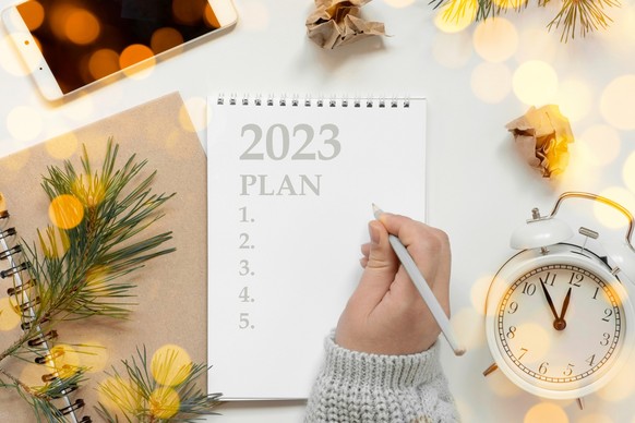 Back to life, goal list concept. Woman's hand writing in empty notebook. Resolutions, plan, goals, checklist, idea concept. Top view, flat lay, copy space. 2023. Christmas, New Year