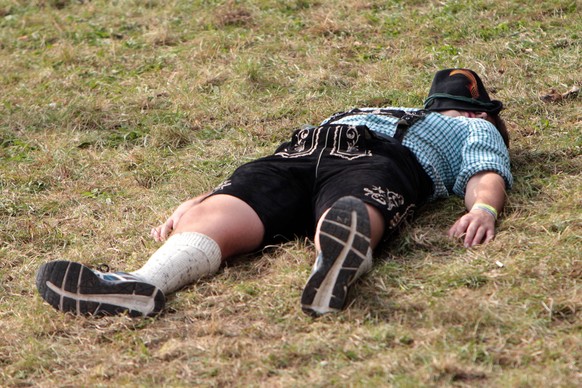 Oktoberfest in M�nchen, Bayern, Deutschland: Mann in Tracht liegt auf dem im Volksmund Kotzh�gel genannten Abhang und schl�ft seinen Rausch aus

Oktoberfest in Munich Bavaria Germany Man in Costume  ...