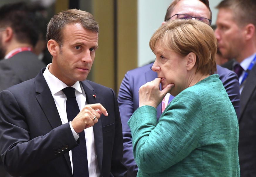 French President Emmanuel Macron, left, speaks with German Chancellor Angela Merkel during a round table meeting at an EU summit in Brussels, Thursday, June 28, 2018. European Union leaders meet for a ...