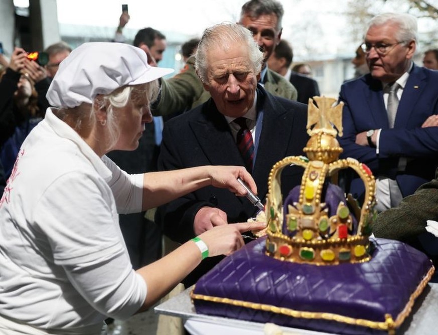 30.03.2023, Brandenburg, Brodowin: König Charles III. von Großbritannien (M) schneidet im Ökodorf Brodowin eine Torte an, die speziell für seinen Besuch angefertigt wurde. Daneben stehen Bundespräside ...